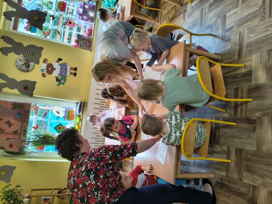 Przedszkolaki siedzą w ozdobionej wielkanocnie Sali i wykonują pracę plastyczną.